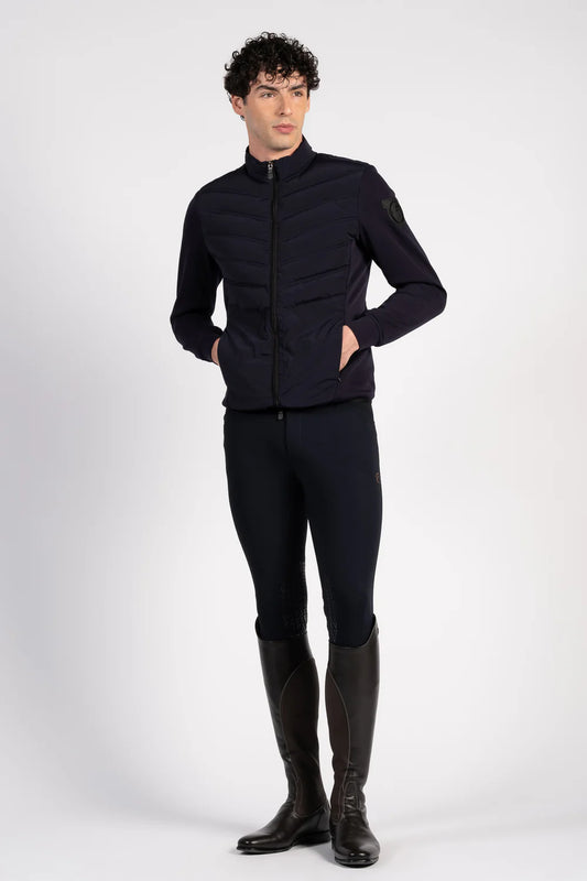 Man wearing a navy equestrian jacket, pants, and boots on a white background