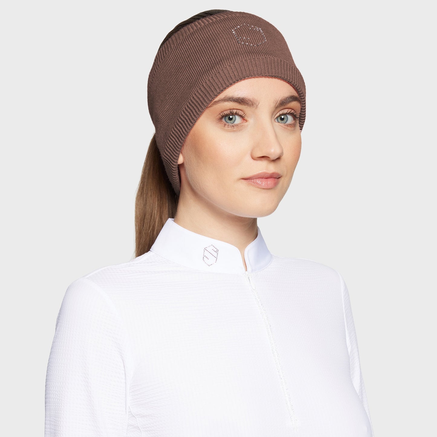 Woman wearing a brown headband with glitzy logo and a white shirt on a white background
