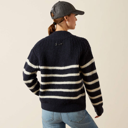 Person wearing a navy and white striped sweater with a cap on a beige background