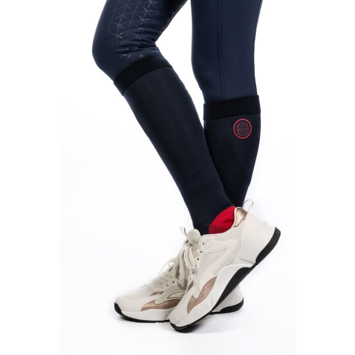 Navy compression sleeves on legs with white sneakers on a white background