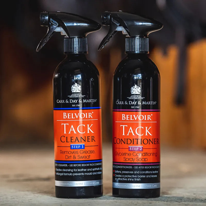 Two bottles of Belvoir Tack Care products on a wooden surface with a blurred background.