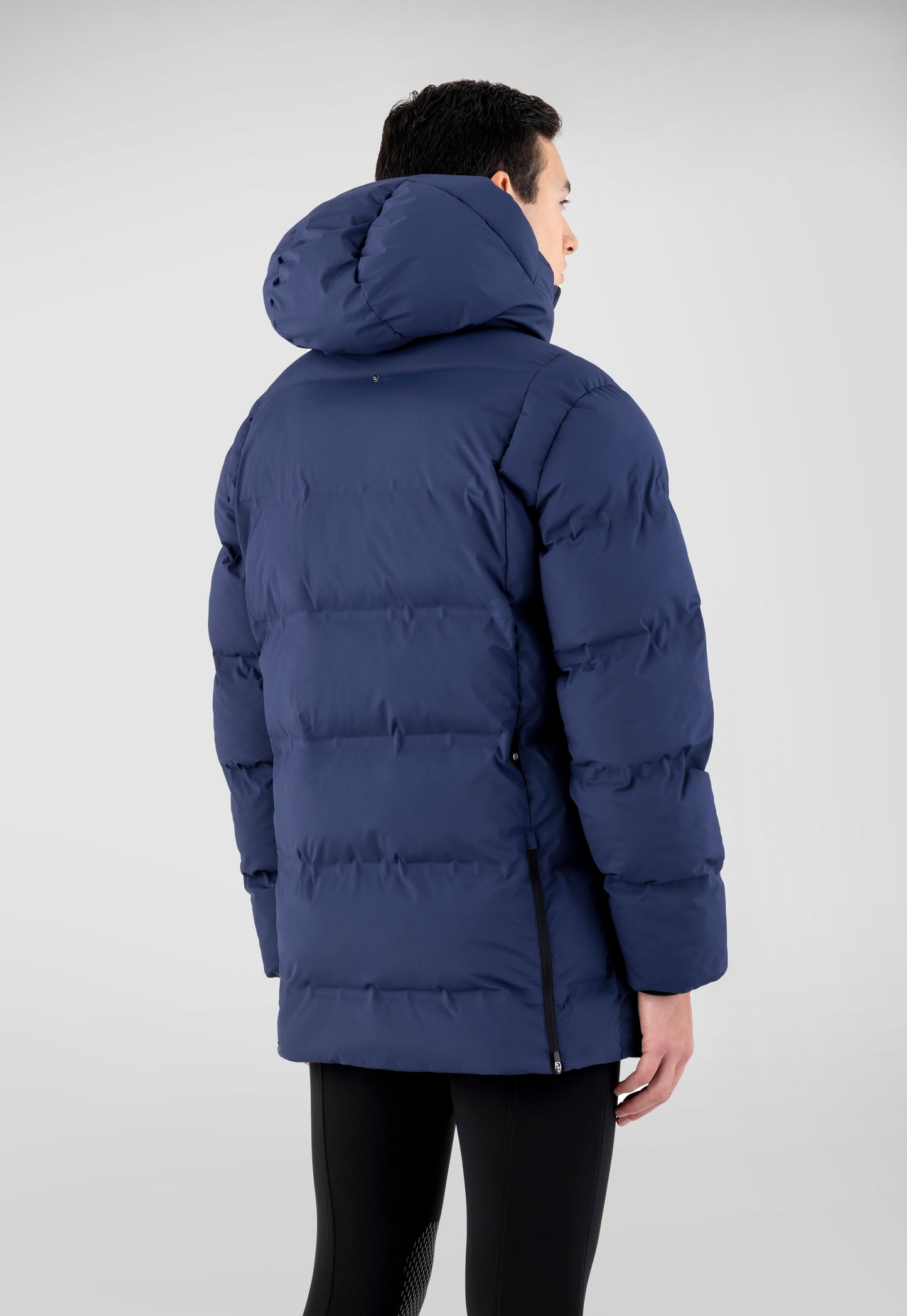 Person wearing a blue puffer jacket on a light gray background