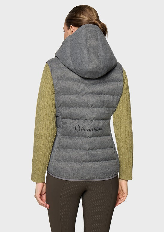 A woman shown from the back wearing a gray hooded puffer vest over olive green cable-knit sleeves, paired with dark brown leggings, against a light gray studio background. The brand name 'Samushill' is embroidered on the back of the vest.