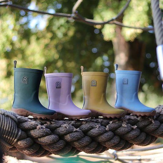 Four different colour wellington boots on a rope with a blurred outside background
