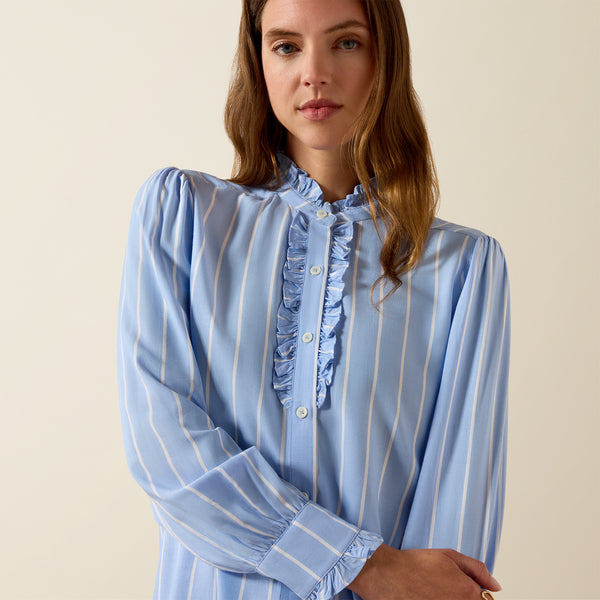 Woman wearing a blue and white striped blouse against a beige background
