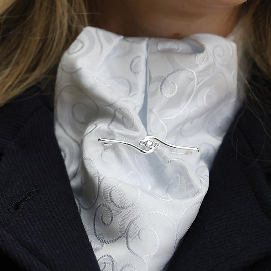 White embroidered scarf with a silver clasp worn by a person