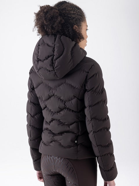 A woman shown from the back wearing a black hooded puffer jacket with horizontal quilted stitching, paired with dark leggings, against a plain light gray studio background.