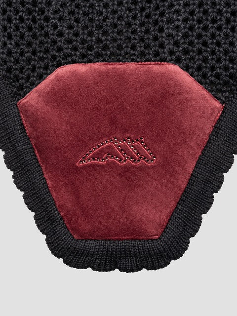 Close-up of a knit accessory with a large burgundy suede-like shield patch featuring an embroidered mountain logo, bordered by black knit trim on a light gray background.