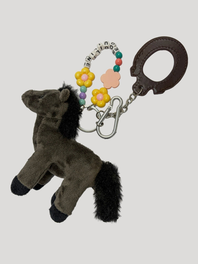 Plush horse keychain with colorful flowers and handcuffs on a light gray background