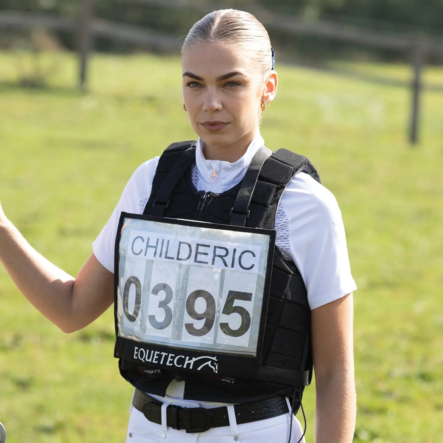 Person wearing an equestrian vest with a visible brand logo in an outdoor setting