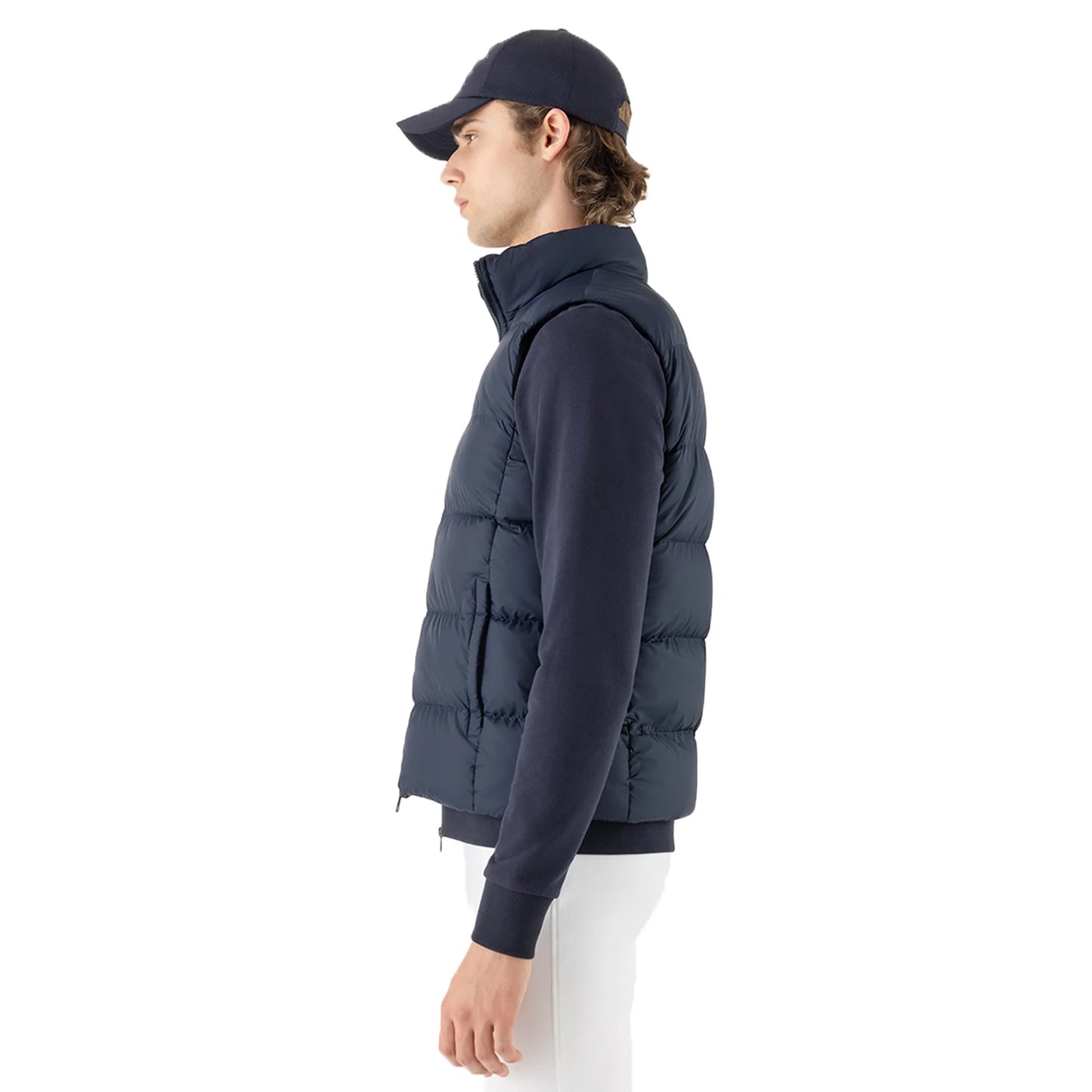 Person wearing a navy puffer vest and cap on a white background