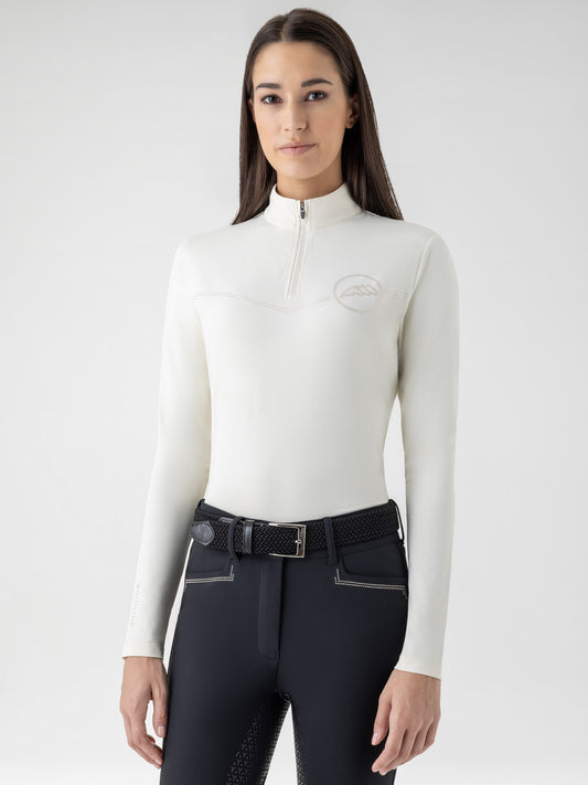 Woman wearing a yellow long-sleeve top and black riding pants on a white background