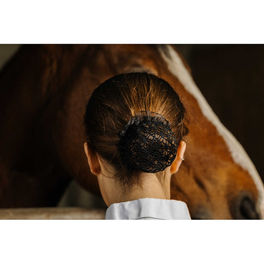 Person with a hairnet standing next to a horse