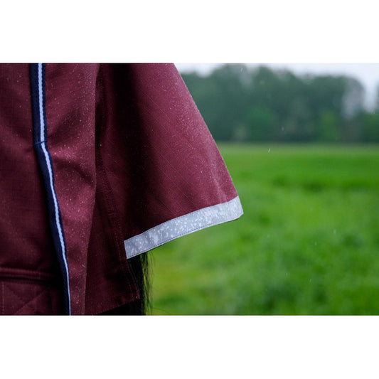 Close-up of a maroon garment with white trim against a blurred green field background