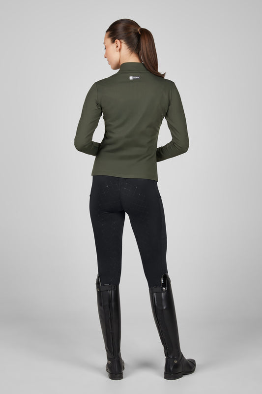 Person wearing a green equestrian jacket, black pants, and black riding boots on a gray background