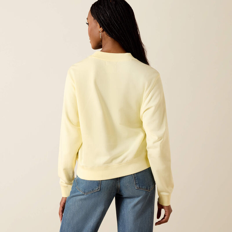 Woman wearing a light yellow sweater and blue jeans on a beige background