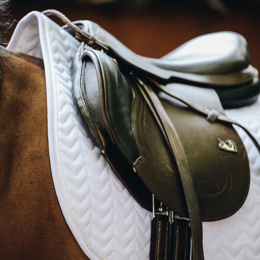 Brown saddle on a horse with a white quilted pad