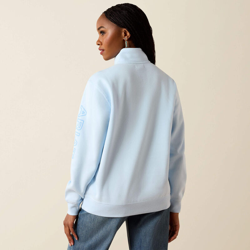 Person wearing a light blue jacket with text on the sleeve against a beige background