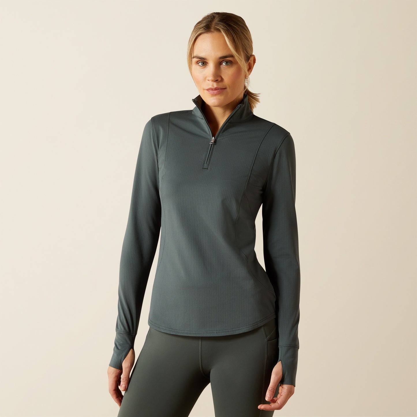 Woman wearing a dark coloured baselayer and legings on a beige backround