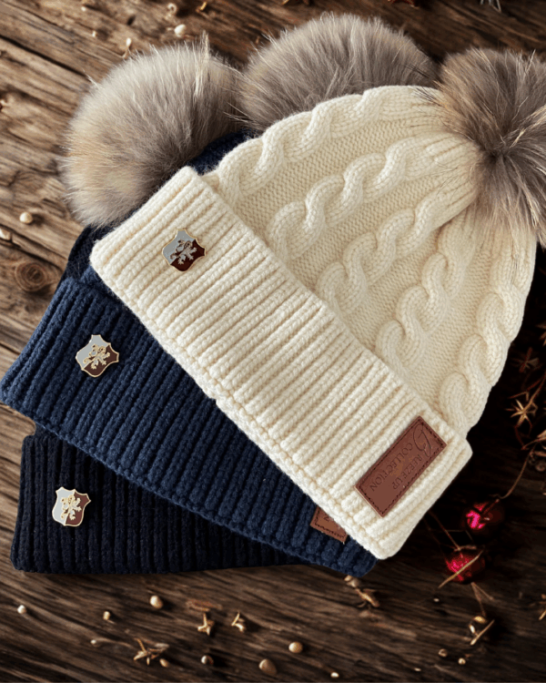Three knit beanies with pom-poms on a wooden surface