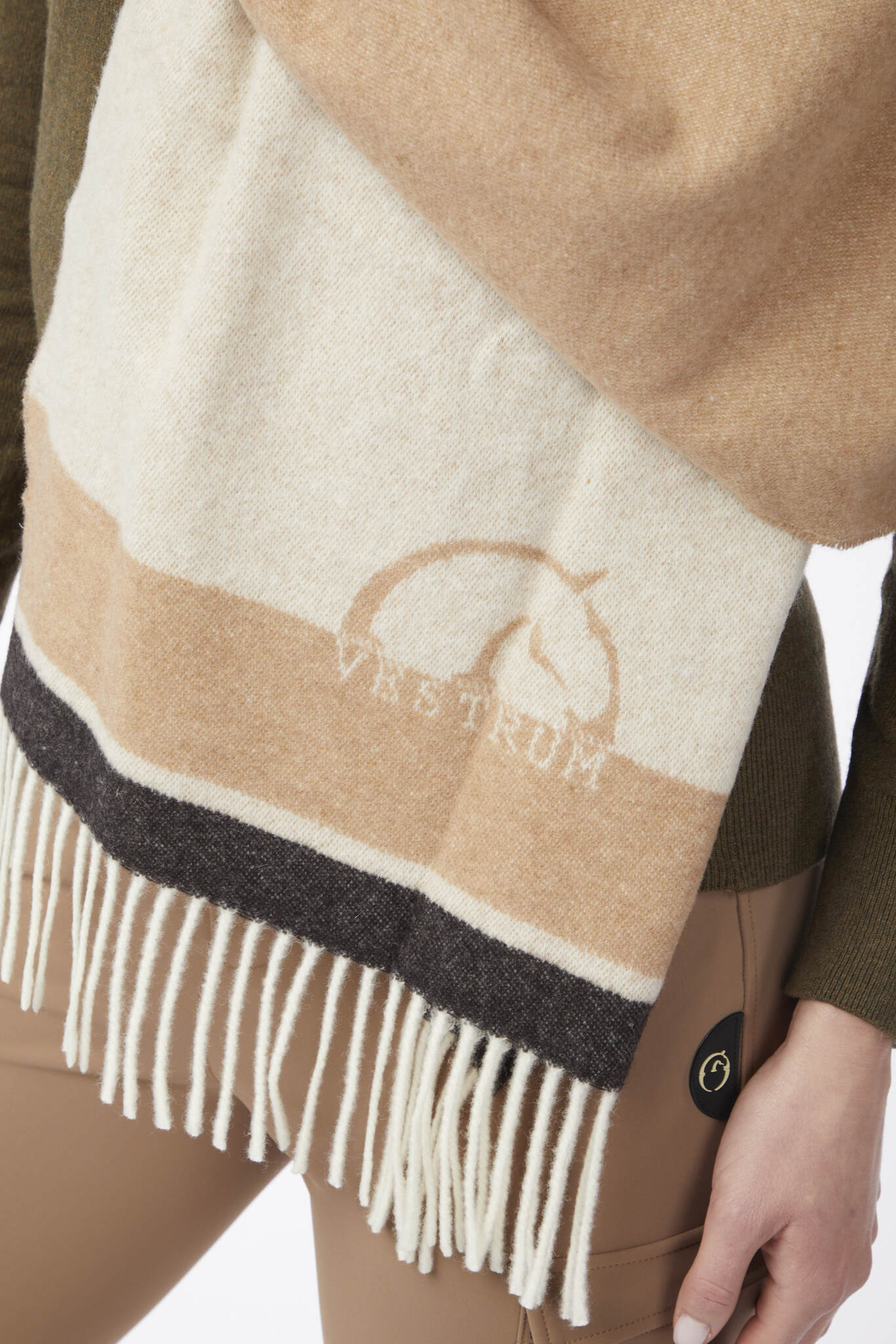 Beige and white scarf with fringe and 'Vestrum' logo worn by a person.