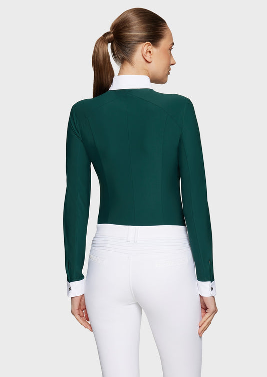 Woman wearing a green competition shirt and white breeches on a beige background