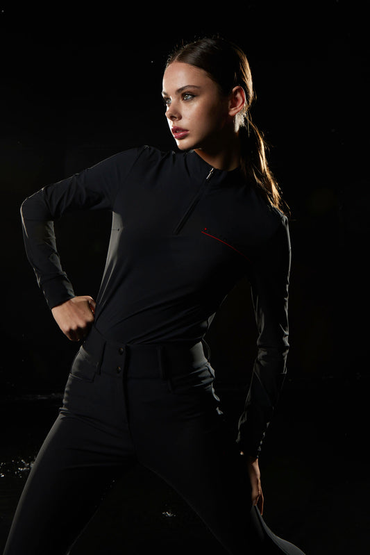Woman in a black outfit against a dark background