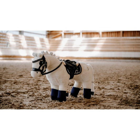 White plush horse toy with black details in an indoor riding arena.