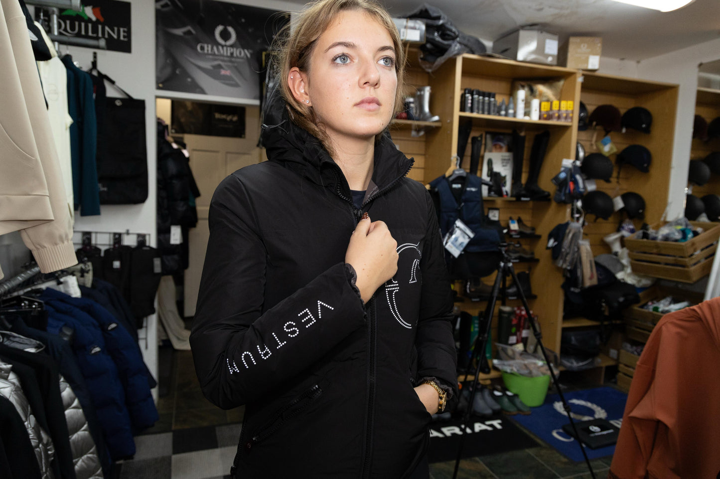 Person wearing a black jacket with 'Vestrum' branding in a store setting.