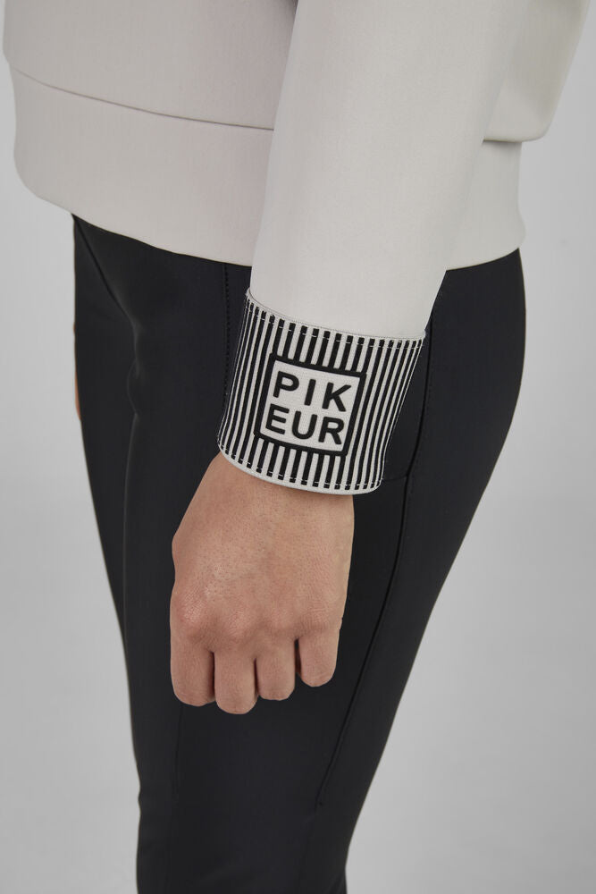 Person wearing a white sleeve with 'PIKEUR' branding on a plain background