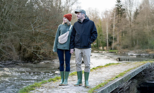 Two people standing by a river with trees in the background