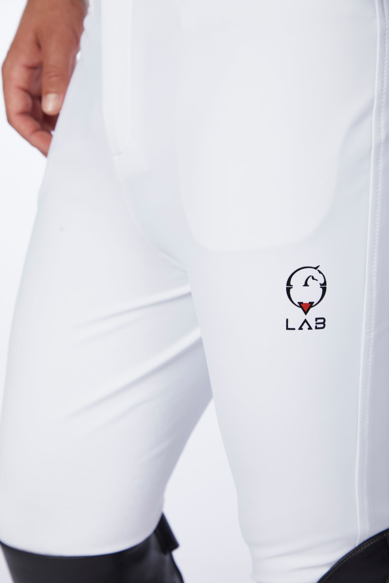 White riding breeches with a logo on the leg, worn by a person.
