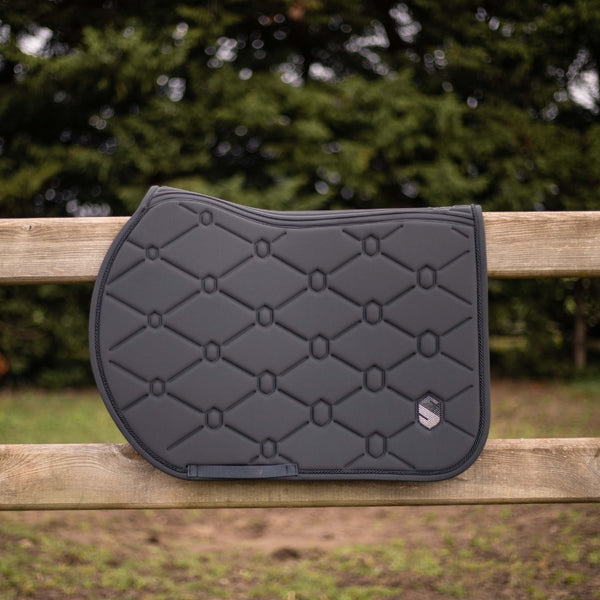 Black quilted saddle pad on a wooden bench with a blurred natural background