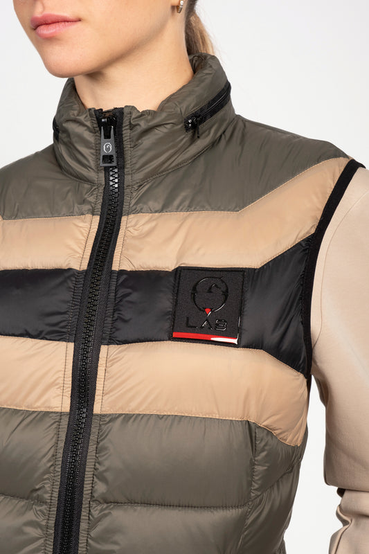 A close-up of a model wearing a puffer vest with horizontal stripes in olive green, beige, and black. The vest features a black zipper, a high collar, and a black chest patch with the LAB brand logo.