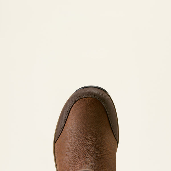 Close-up top view of a brown leather boot toe showing the pebbled texture and dark trim against a solid off-white background.