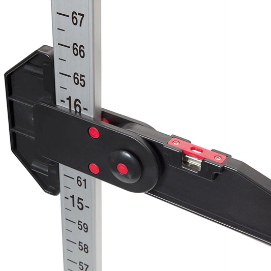 Close-up of a black and silver measuring device with red adjustment knobs and red markings, showing a vertical ruler scale on a white background.