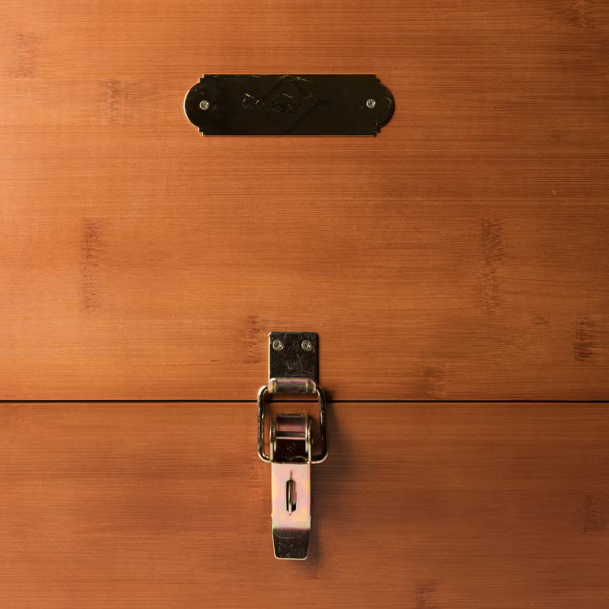 Close-up of a wooden surface with a metal latch and decorative plate.