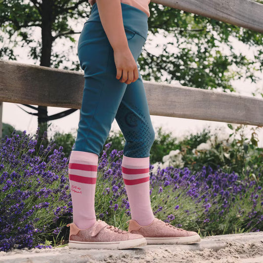 Person wearing pink socks with red stripes standing in a garden with lavender flowers.