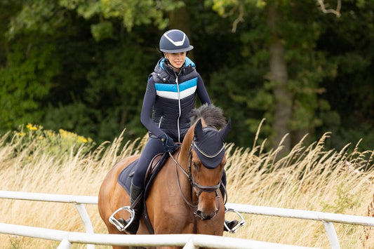 Person riding a horse in an outdoor setting with trees and grass.
