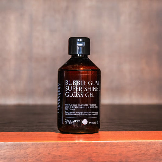 Bottle of Bubble Gum Super Shine Gloss Gel on a wooden surface with a blurred background