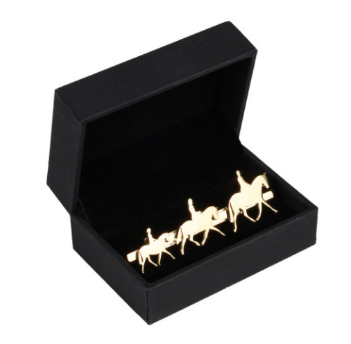Gold horse and rider pin in a black box on a white background
