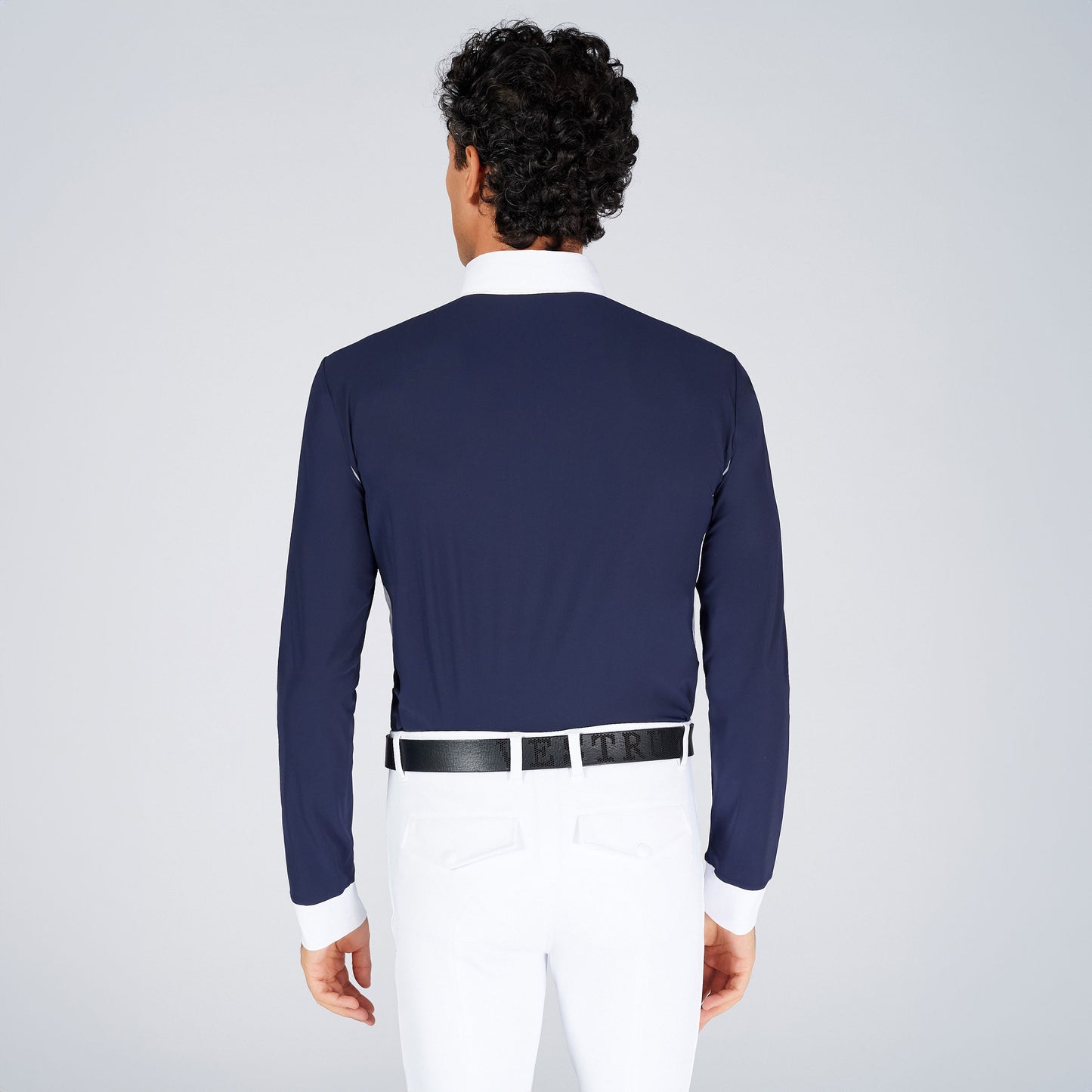 Man wearing a navy long-sleeve shirt and white pants on a light gray background