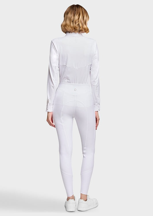 A woman viewed from the back wearing a white long-sleeve collared top and matching white fitted pants, paired with white sneakers, against a light gray studio background.