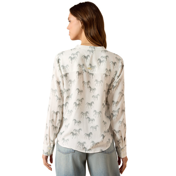 Woman wearing a white blouse with horse pattern on a white background