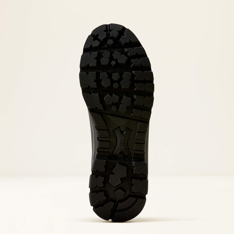 A close-up view of a black rubber shoe sole with deep tread patterns, shown against a plain off-white background.