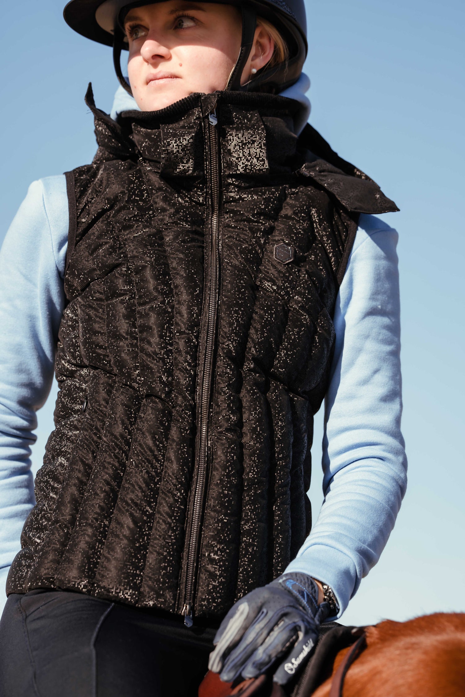 Lady wearing a samshield gilet riding a chestnut horse