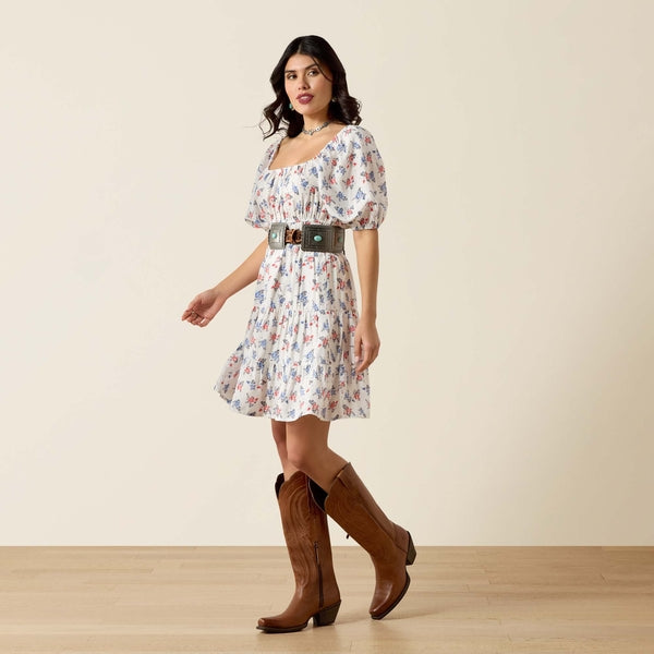Girl in a floral dress and wearing brown cowboy boots on a beige background 
