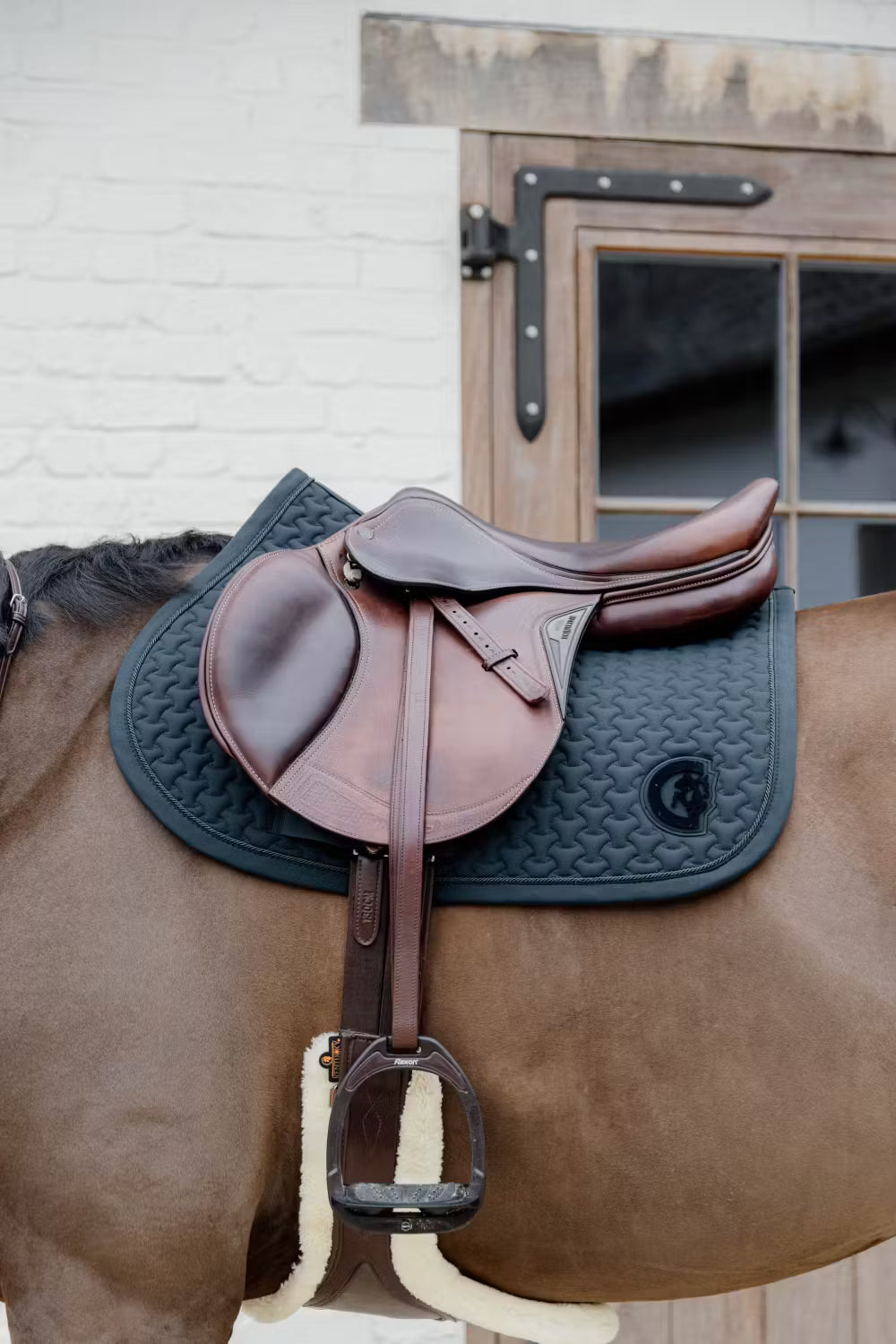 Brown saddle with a green saddle pad on a bay horse