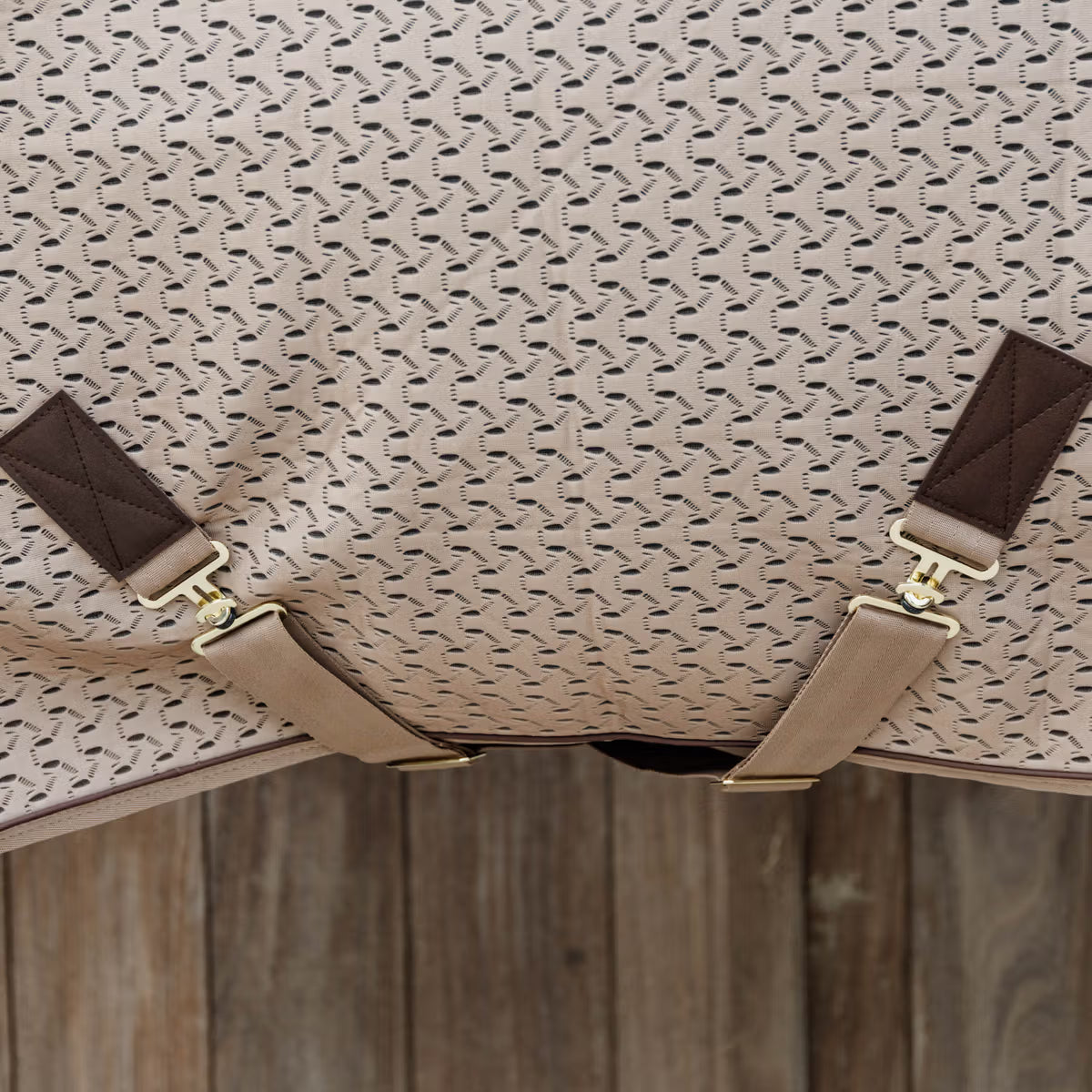 Patterned fabric with brown straps and gold hardware on a wooden surface