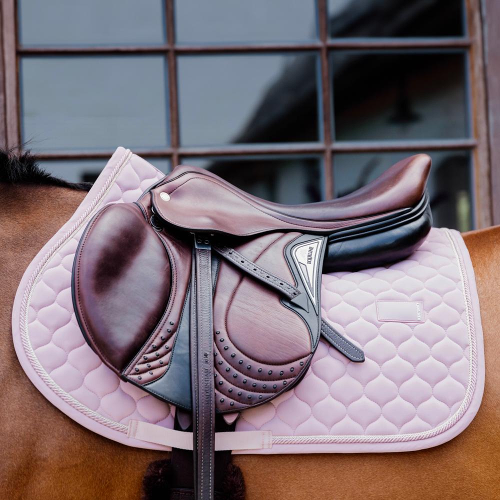 Pink saddlepad under a brown saddle on a bay horse